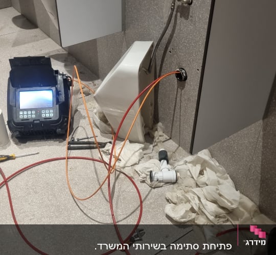 כלי עבודה וצינורות ליד אסלה בשירותים